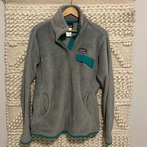 Grey Patagonia pullover sweater with green trim edging.